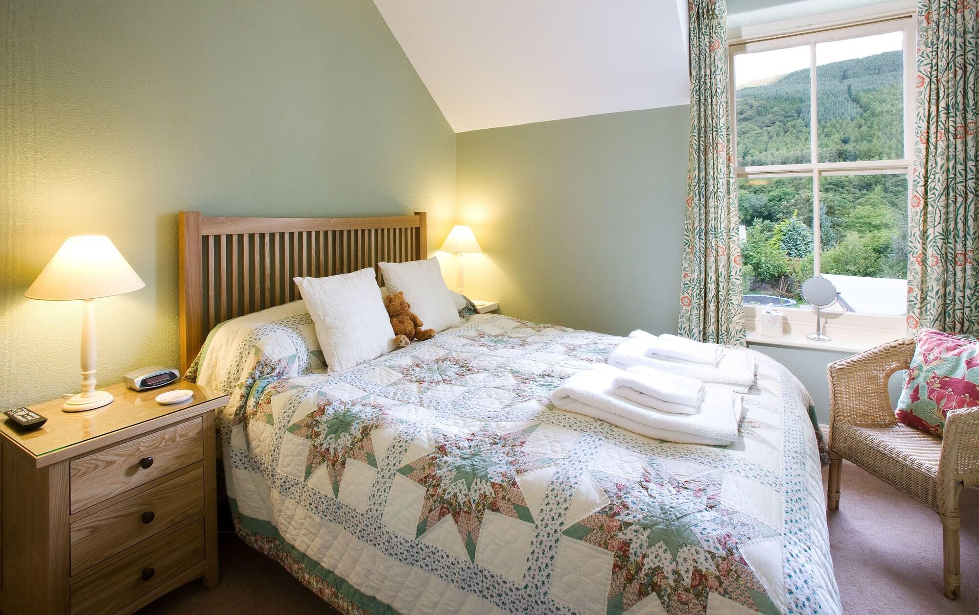 Double bedroom with patchwork quilt and mountain-view window