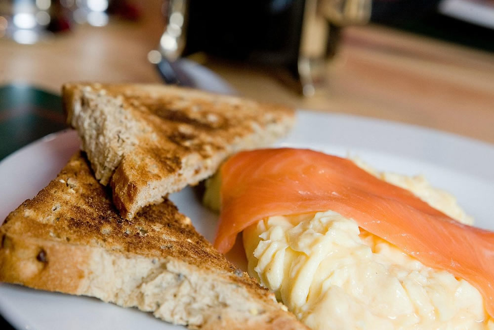 Smoked salmon and scrambled eggs on toast with orange juice