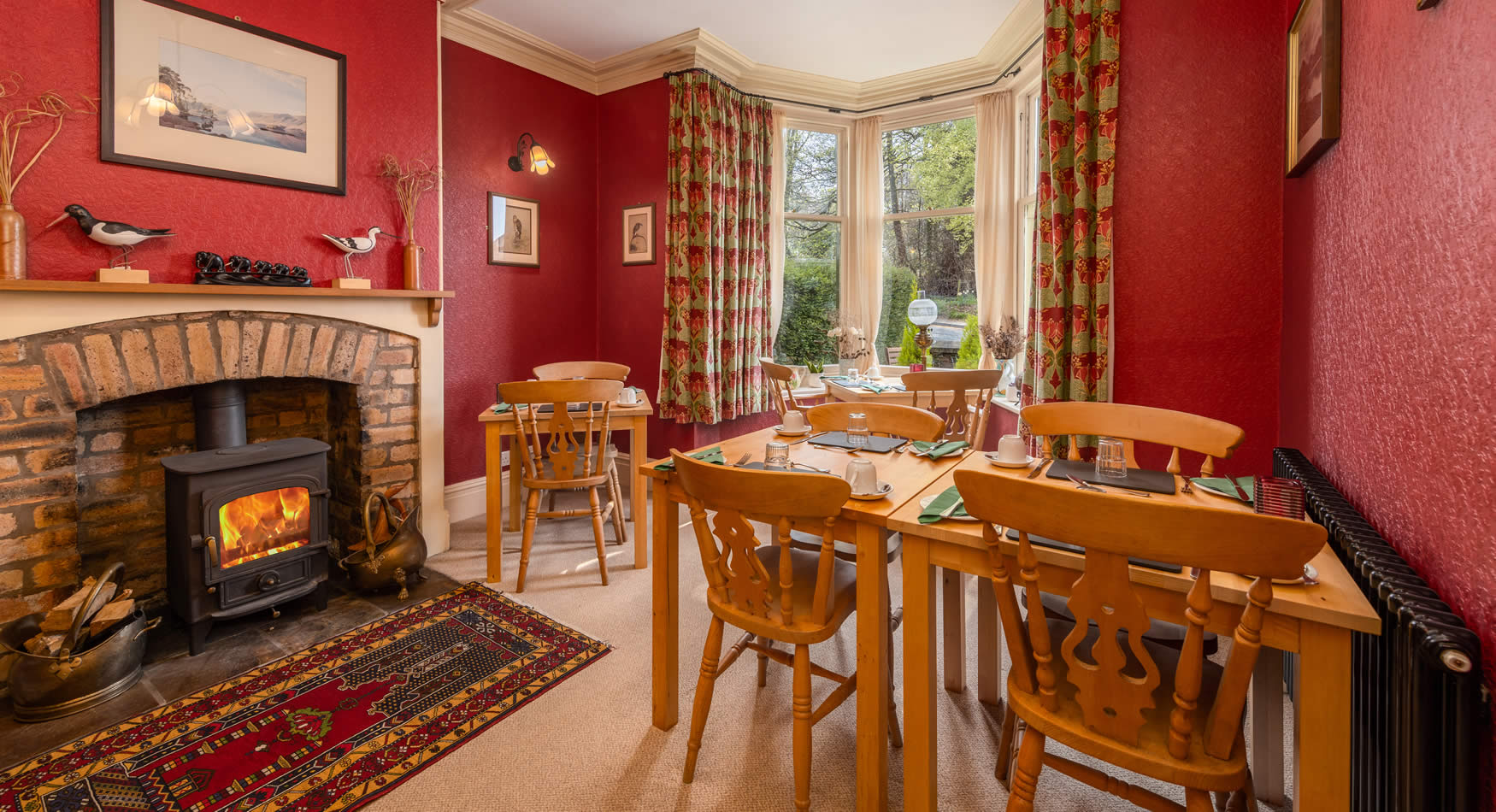 The red dining room with wood burner, set for breakfast in the bay window